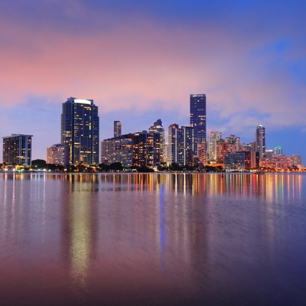 Miami city skyline panorama at dusk with urban skyscrapers over sea with reflection